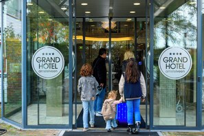A hotel entrance with glass doors and a sign reading "Grand Hotel Amsterdam." - Grand Hotel Amstelveen (Amstelveen)