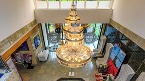 A hotel lobby with a central chandelier, seating areas, and a reception desk. - Grand Hotel Amstelveen (Amstelveen)