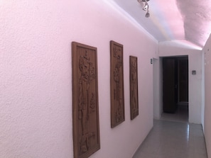 A hallway with three wooden carvings on the wall and a door at the end. - Caribo Cozumel (Cozumel)