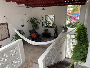 A hammock chair in a room with a tiled floor, a ceiling fan, and potted plants. - Caribo Cozumel (Cozumel)
