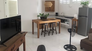 A modern kitchen with a wooden table, bar stools, a TV, and a refrigerator.