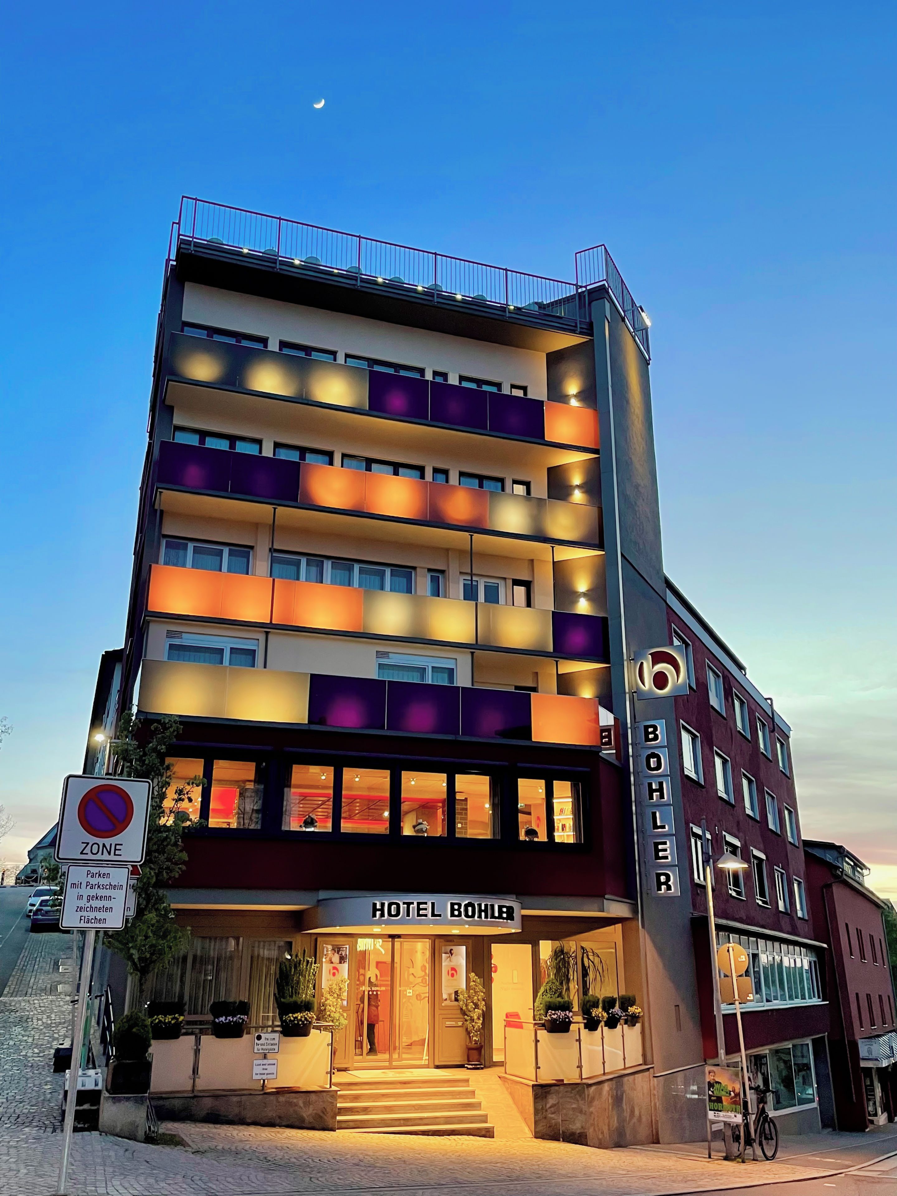 Ein mehrstöckiges Hotel mit einem markanten Eingang, Balkonen und einem Schild, das eine Parkverbotszone kennzeichnet.