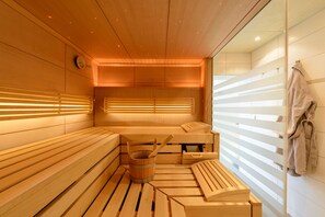 Una sauna con bancos de madera, un cubo de madera y un perchero para toallas.