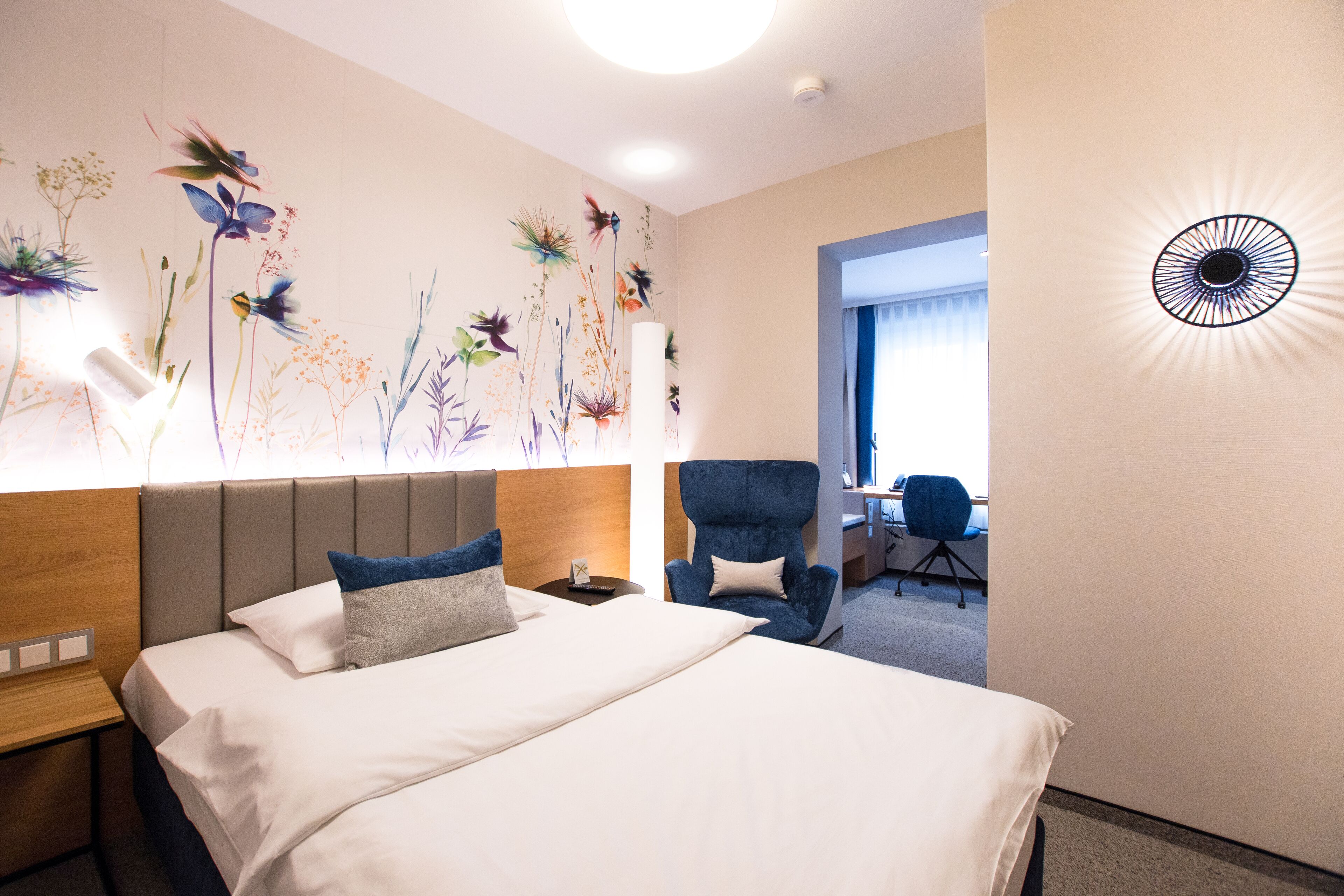 A hotel room with a bed, a desk, and a chair.