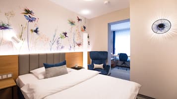 A hotel room with a bed, a desk, and a chair.