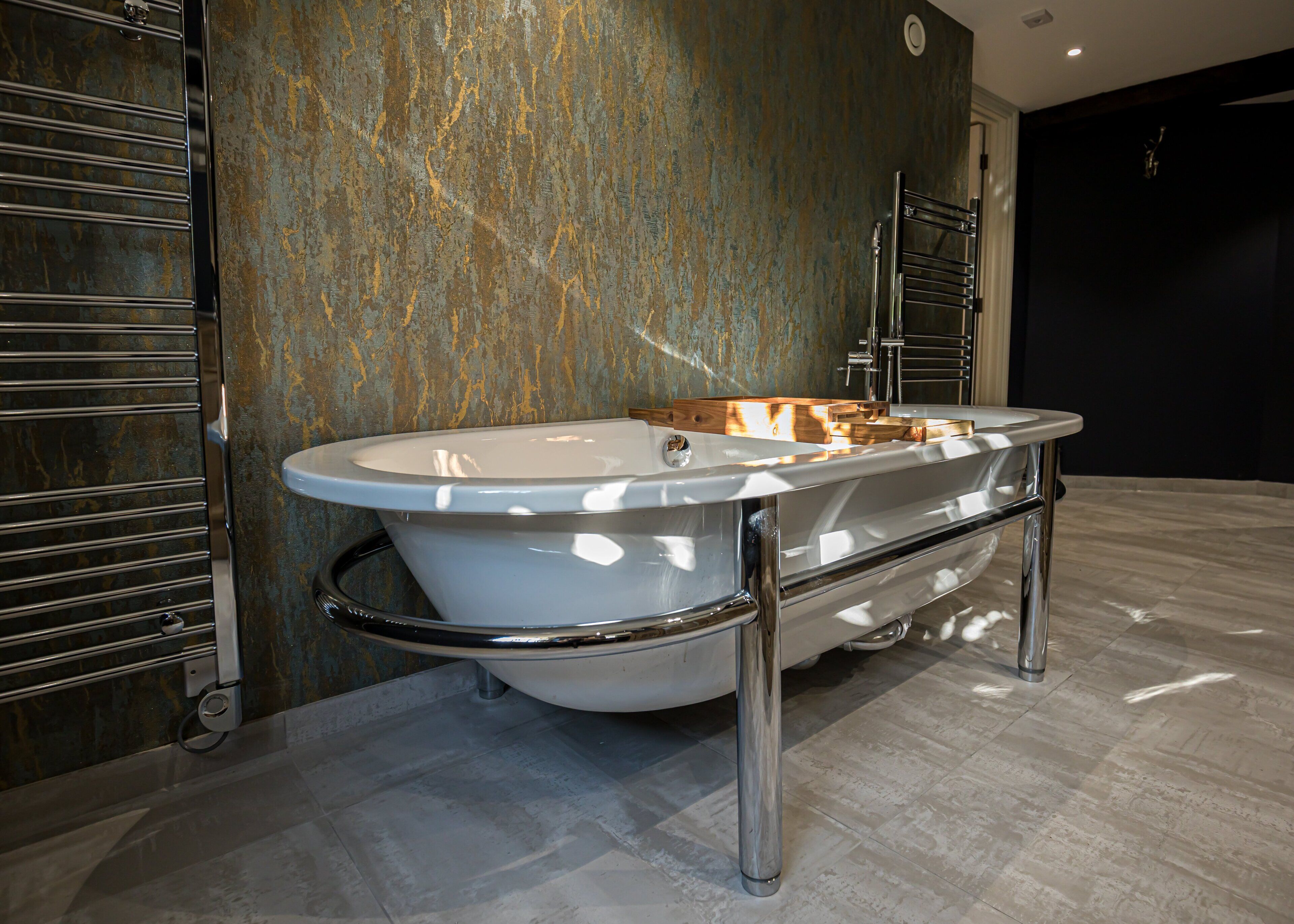 A modern bathroom with a freestanding bathtub, chrome fixtures, and a textured wall.