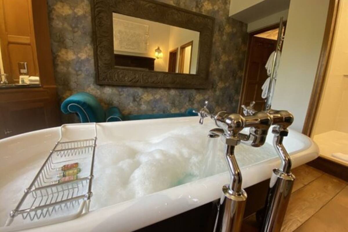 Un baño con bañera, espejo y toallero.