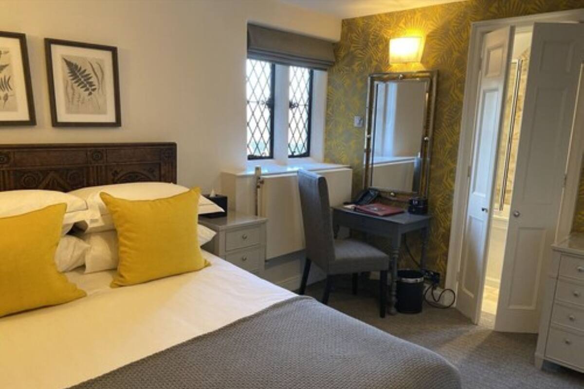 Habitación de hotel con cama, escritorio, silla, espejo y armario.