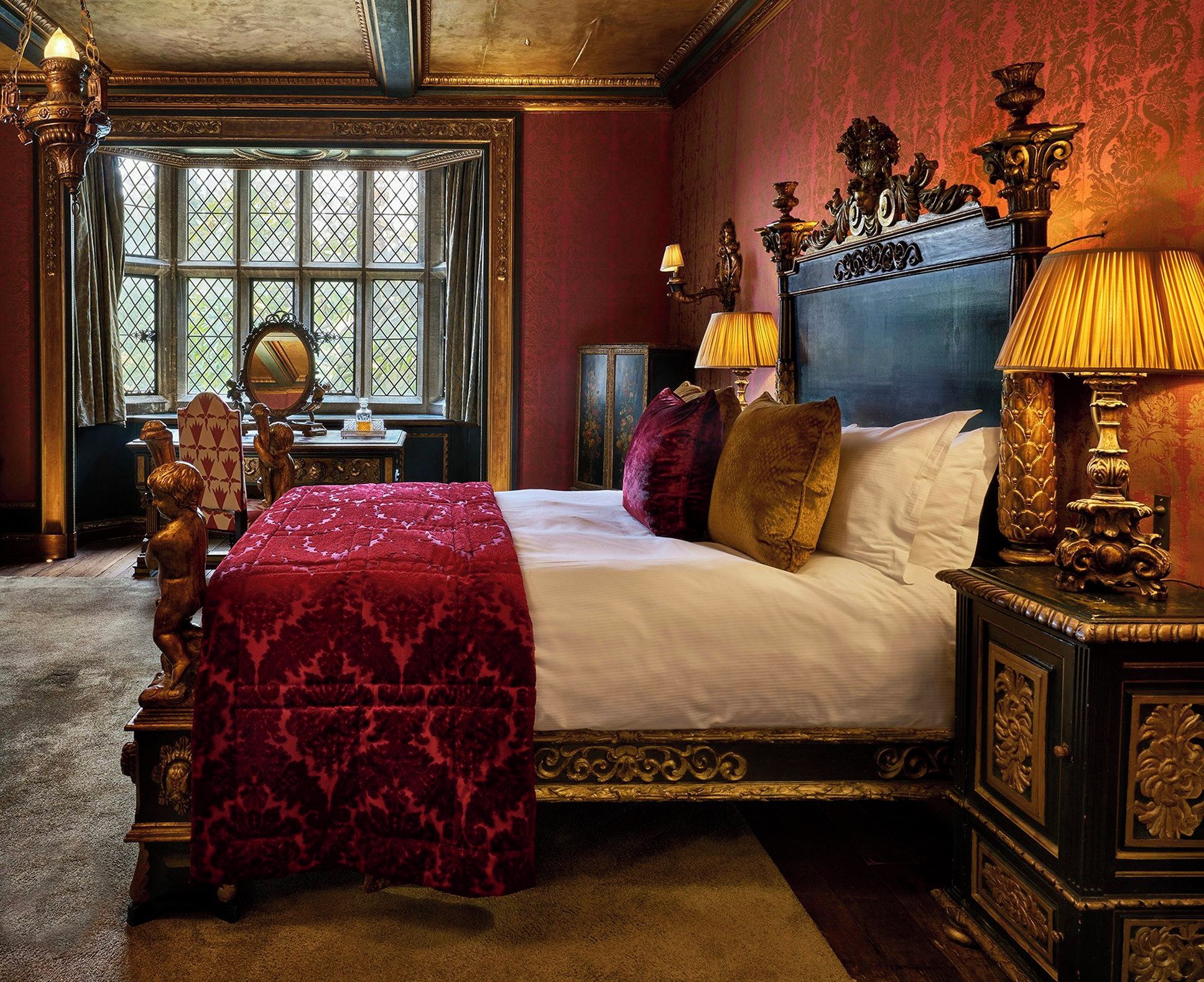 A bedroom with a large bed, ornate headboard, and a window with a view.