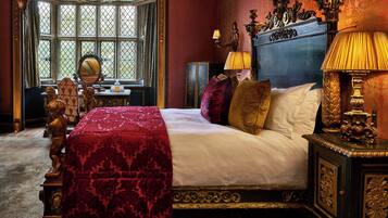 A bedroom with a large bed, ornate headboard, and a window with a view.