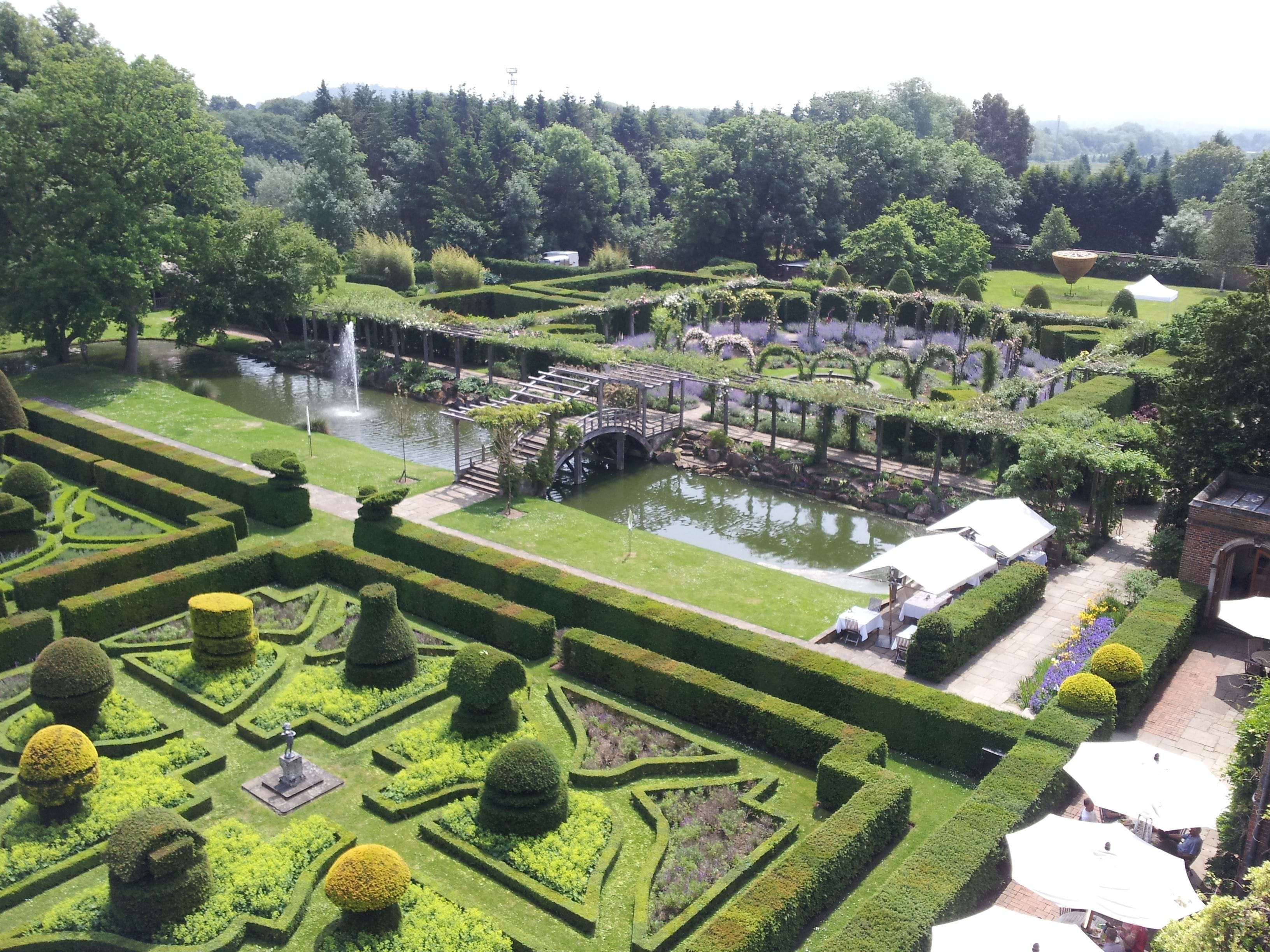 A formal garden with geometric hedges, a central water feature, and a gazebo.