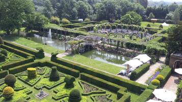 A formal garden with geometric hedges, a central water feature, and a gazebo.