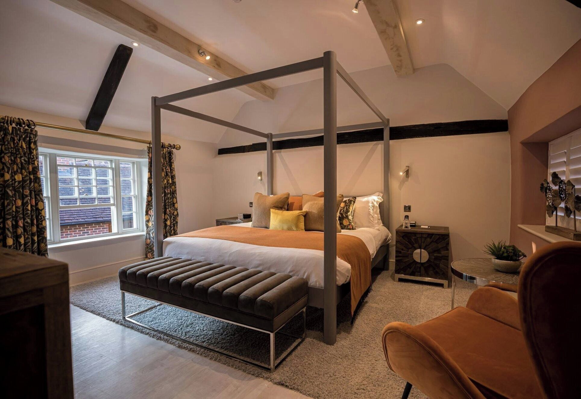 Una camera da letto con un letto a baldacchino, un comodino, una sedia e una finestra con tende.