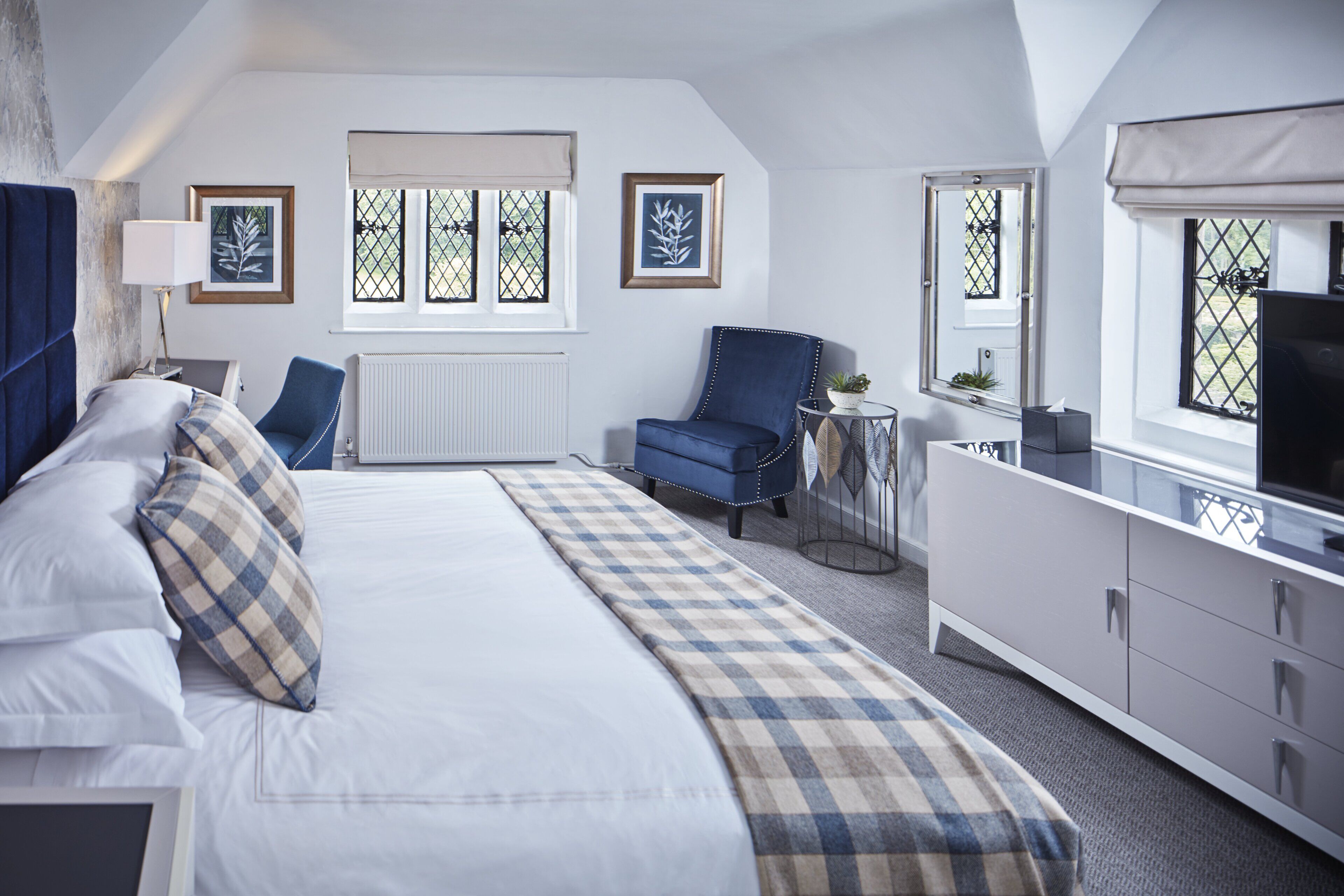 A bedroom with a bed, a chair, a TV, and a dresser.