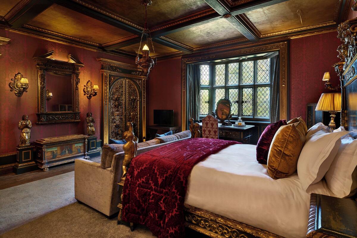 Un dormitorio lujoso con una cama grande, muebles ornamentales y un ventanal que deja entrar luz natural.