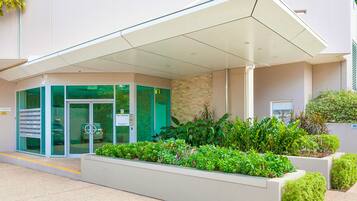 A modern building entrance with a covered waiting area, a glass door entrance, and a fire control sign.