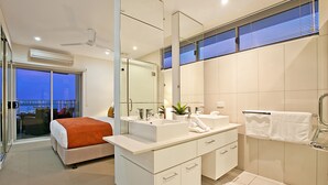 A modern hotel room with a large bed, a bathroom with a large mirror, and a balcony with a view. - Beachlife Holiday Apartments (Darwin)