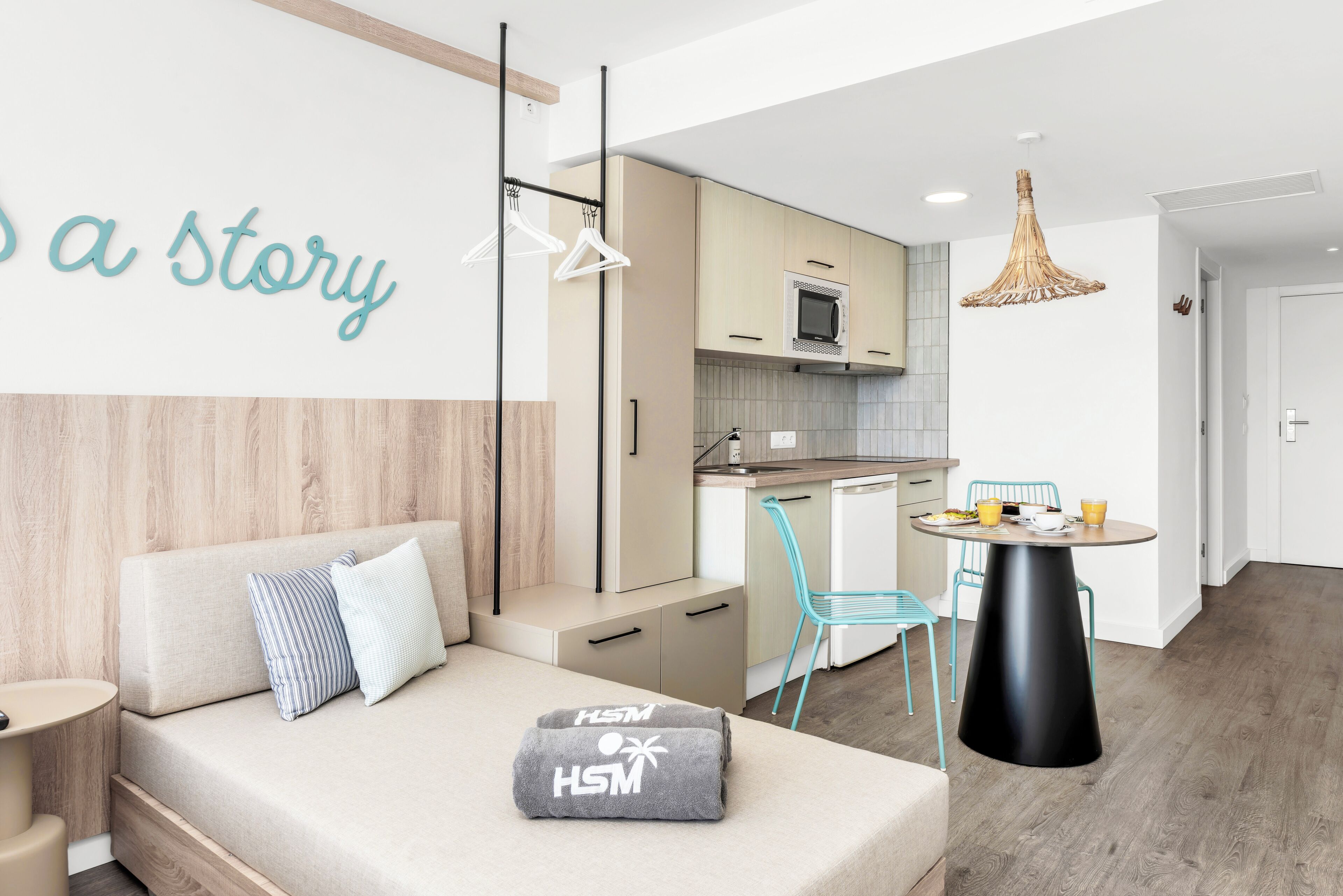 A modern, compact living space with a kitchenette, a dining area, and a sofa with a pillow.