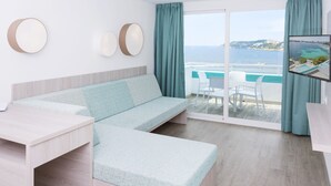 Une pièce moderne avec un canapé de couleur claire, une petite table et un téléviseur fixé au mur.