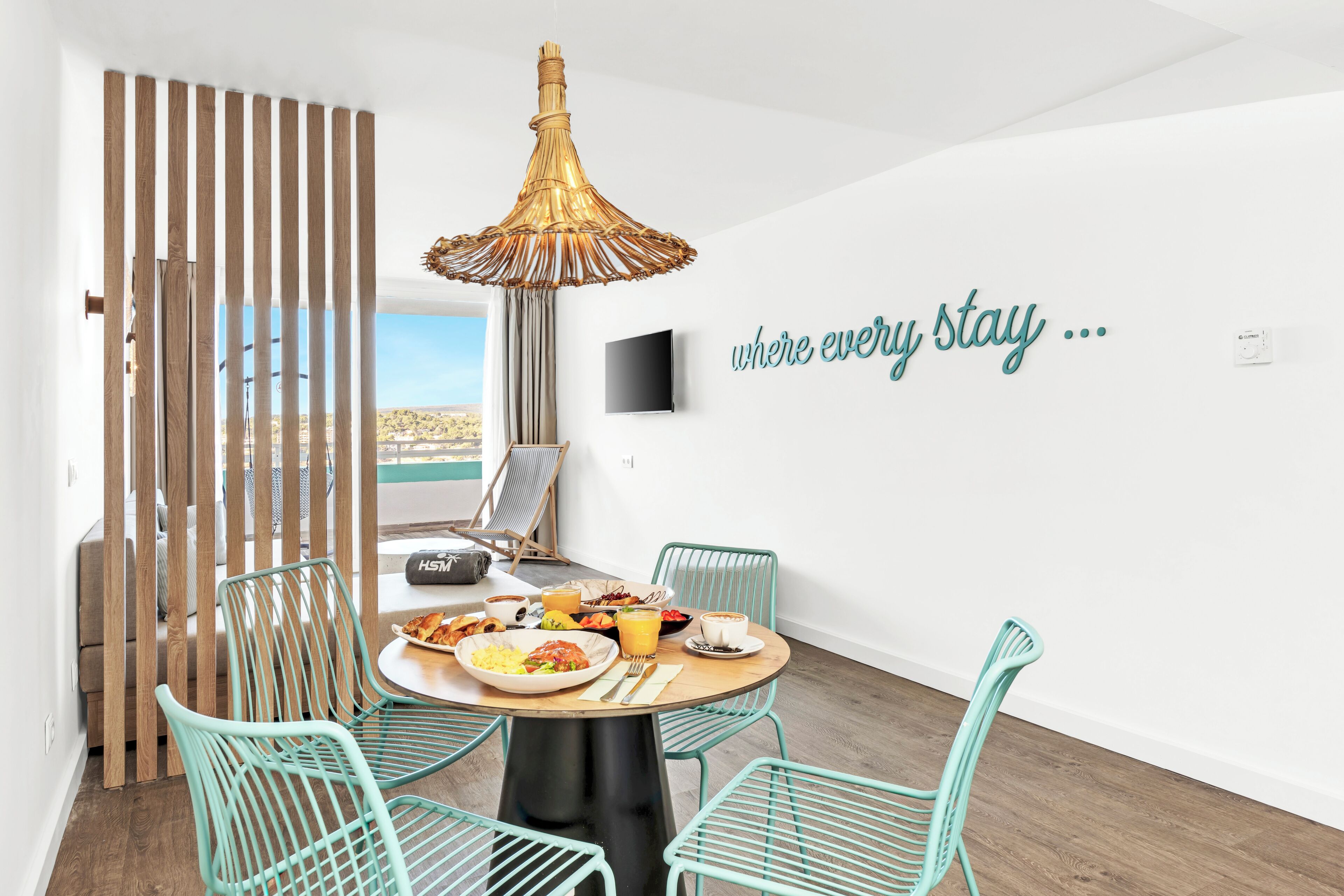 Un'area pranzo moderna con un tavolo rotondo, sedie color petrolio e un lampadario decorativo.
