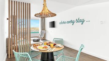 Un'area pranzo moderna con un tavolo rotondo, sedie color petrolio e un lampadario decorativo.