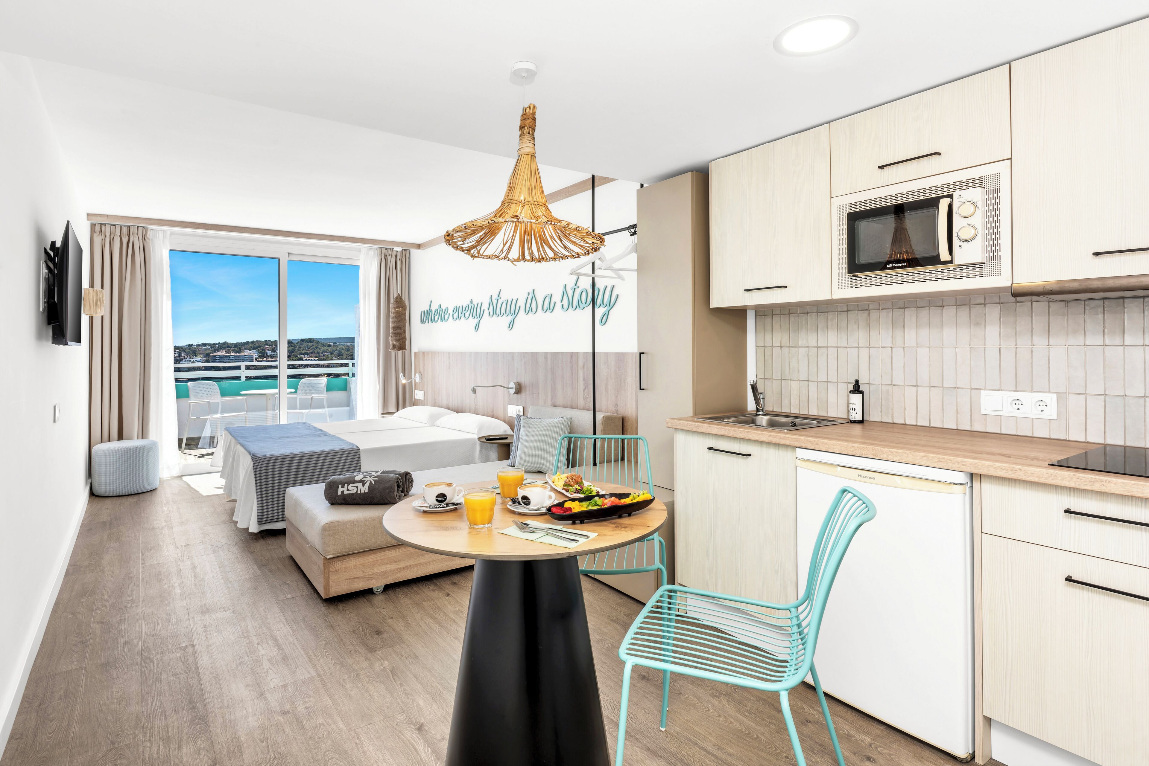 Una habitación de hotel moderna con balcón, zona de comedor con desayuno y kitchenette.