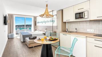 Et moderne hotelværelse med balkon, spiseområde med morgenmad og tekøkken.