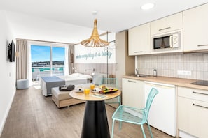A modern hotel room with a balcony, a dining area with breakfast, and a kitchenette. - Hotel HSM Sándalo Beach (Calvia)