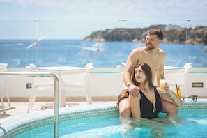 A couple in a swimming pool with a view of the sea and a distant island. - Hotel HSM Sándalo Beach (Calvia)