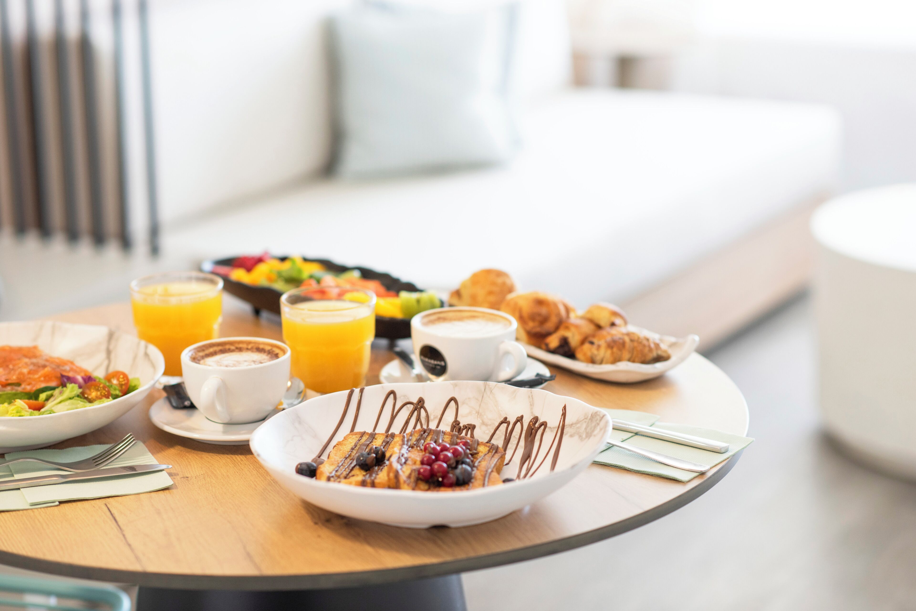 A breakfast setting with a variety of food items, including a plate of pancakes, a bowl of fruit, and a cup of coffee.