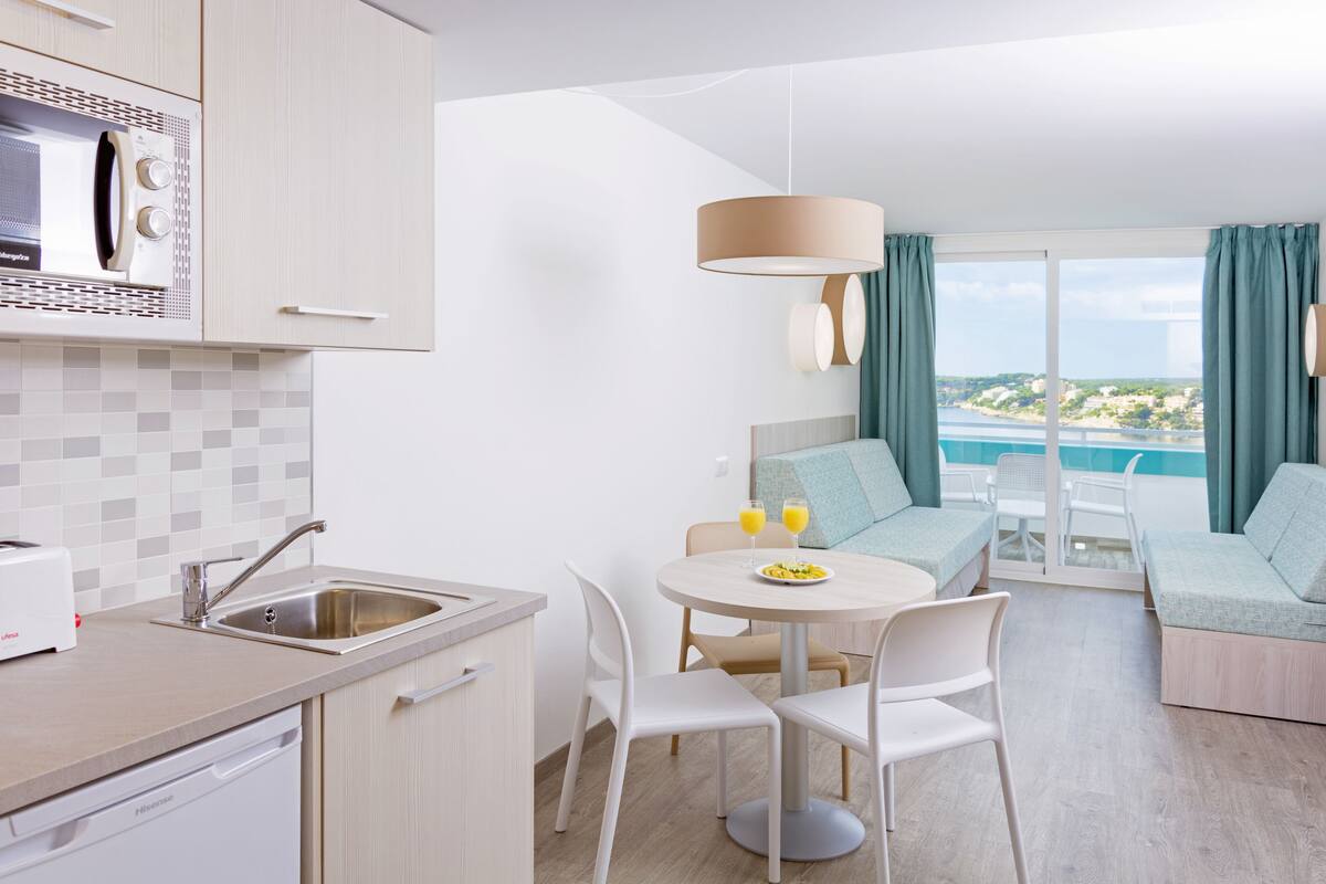 A modern kitchen with a microwave, sink, and a dining area with a table and chairs.