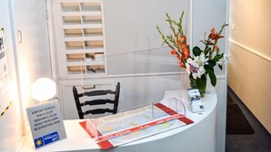 En reception med en lysekrone, en stol, en vase med blomster og et skilt med information om lufthavnen.