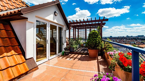 Eine Dachterrasse mit einer Pergola, Pflanzkübeln und Blick auf die Stadt.
