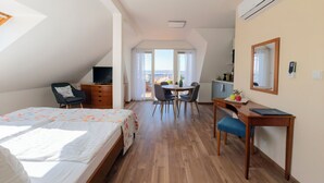 Ein Schlafzimmer mit Bett, Schreibtisch, Stuhl, Fernseher und einem Balkon mit Aussicht.