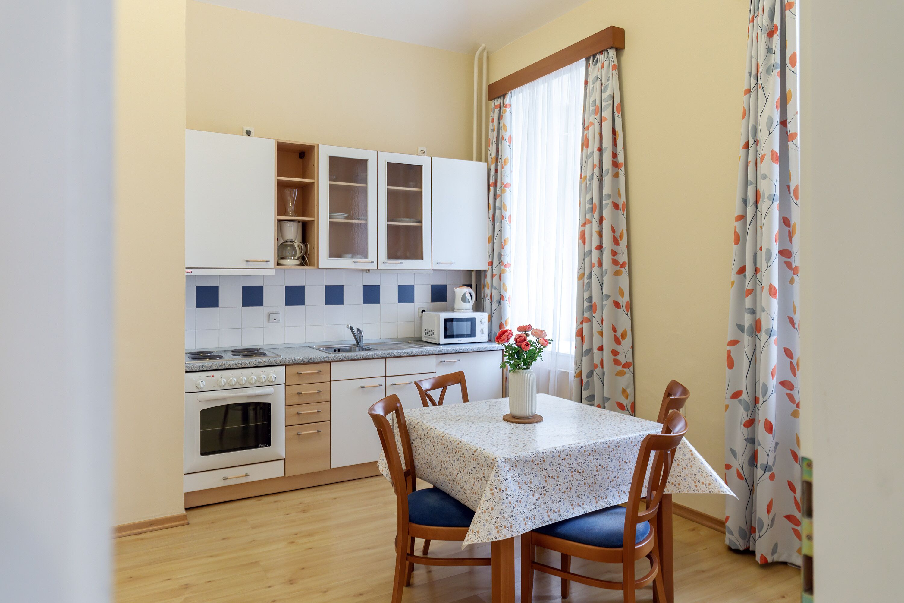 Una cocina compacta con armarios blancos, un microondas y una mesa de comedor con sillas.