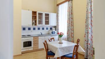 Una cocina compacta con armarios blancos, un microondas y una mesa de comedor con sillas.