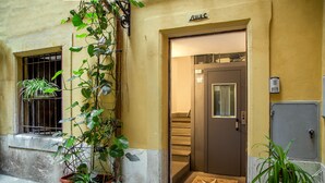 Entrada de un edificio con una puerta que indica “CALAC”, una planta en maceta y un felpudo de baldosas.