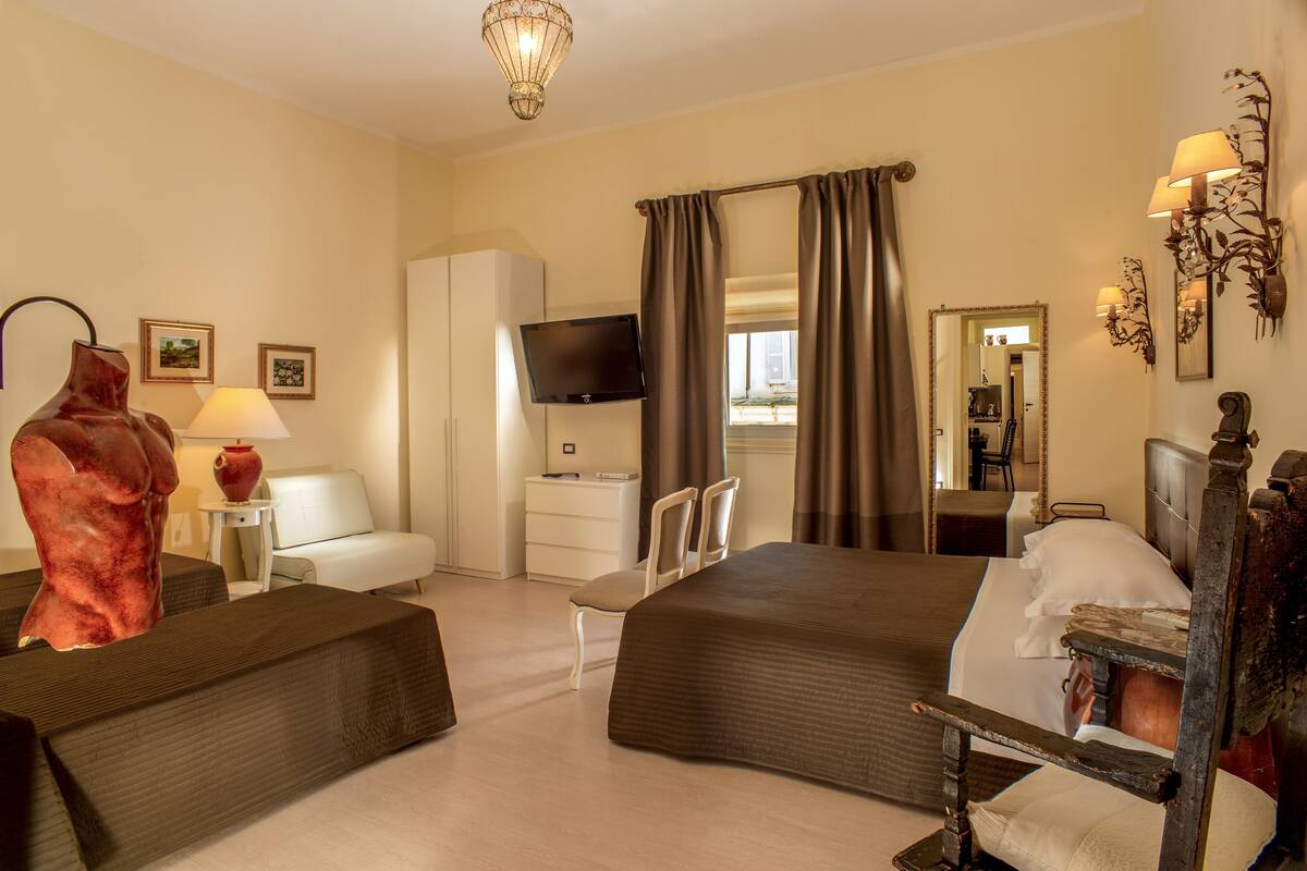 Une chambre d’hôtel avec un grand lit, une télévision, un bureau, une chaise et une armoire.