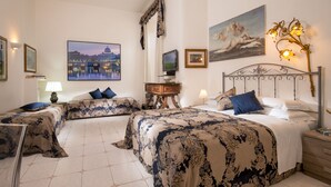 Habitación de hotel con dos camas, una televisión, una mesita de noche y obras de arte en las paredes.