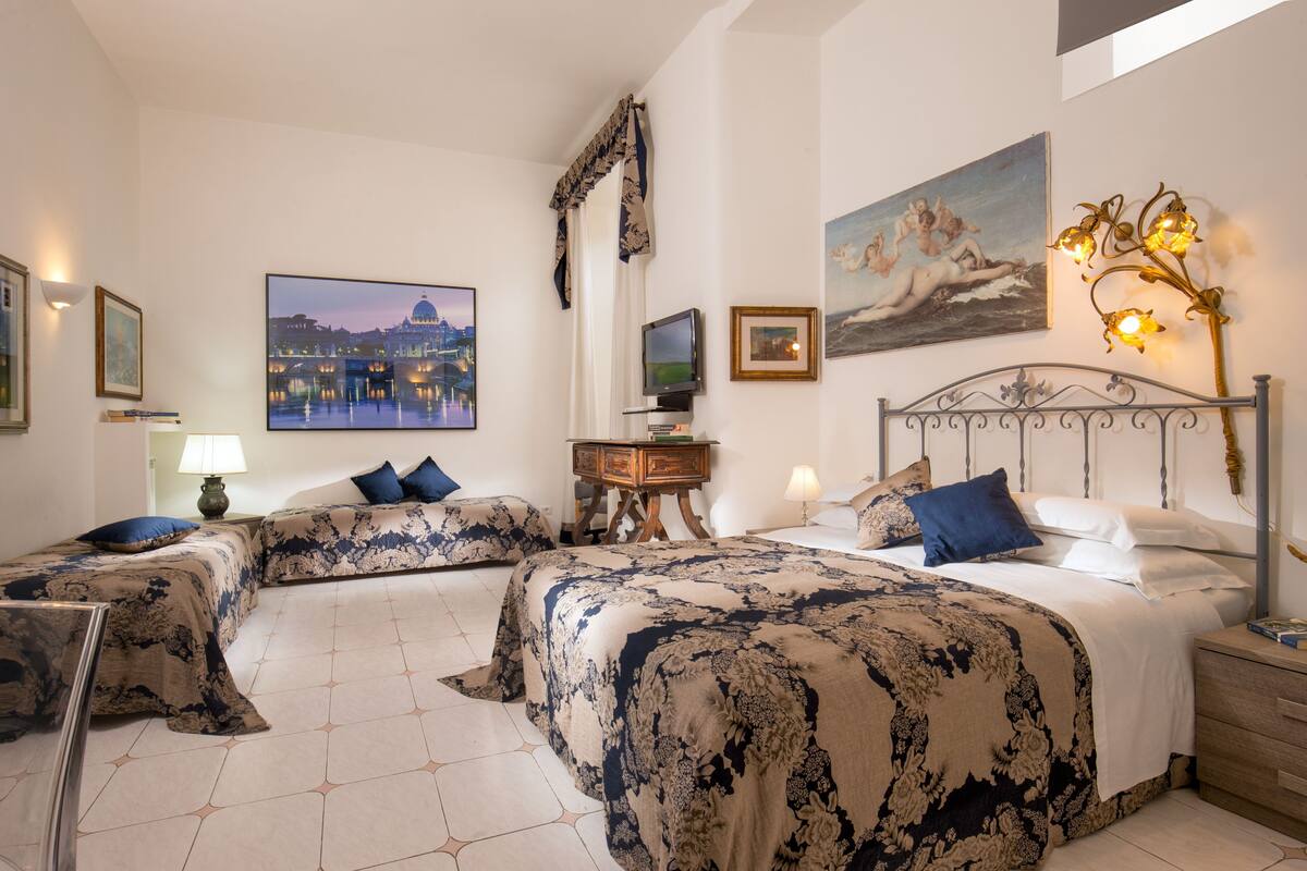 Une chambre d’hôtel avec deux lits, une télévision, une table de chevet et des œuvres d’art accrochées aux murs.