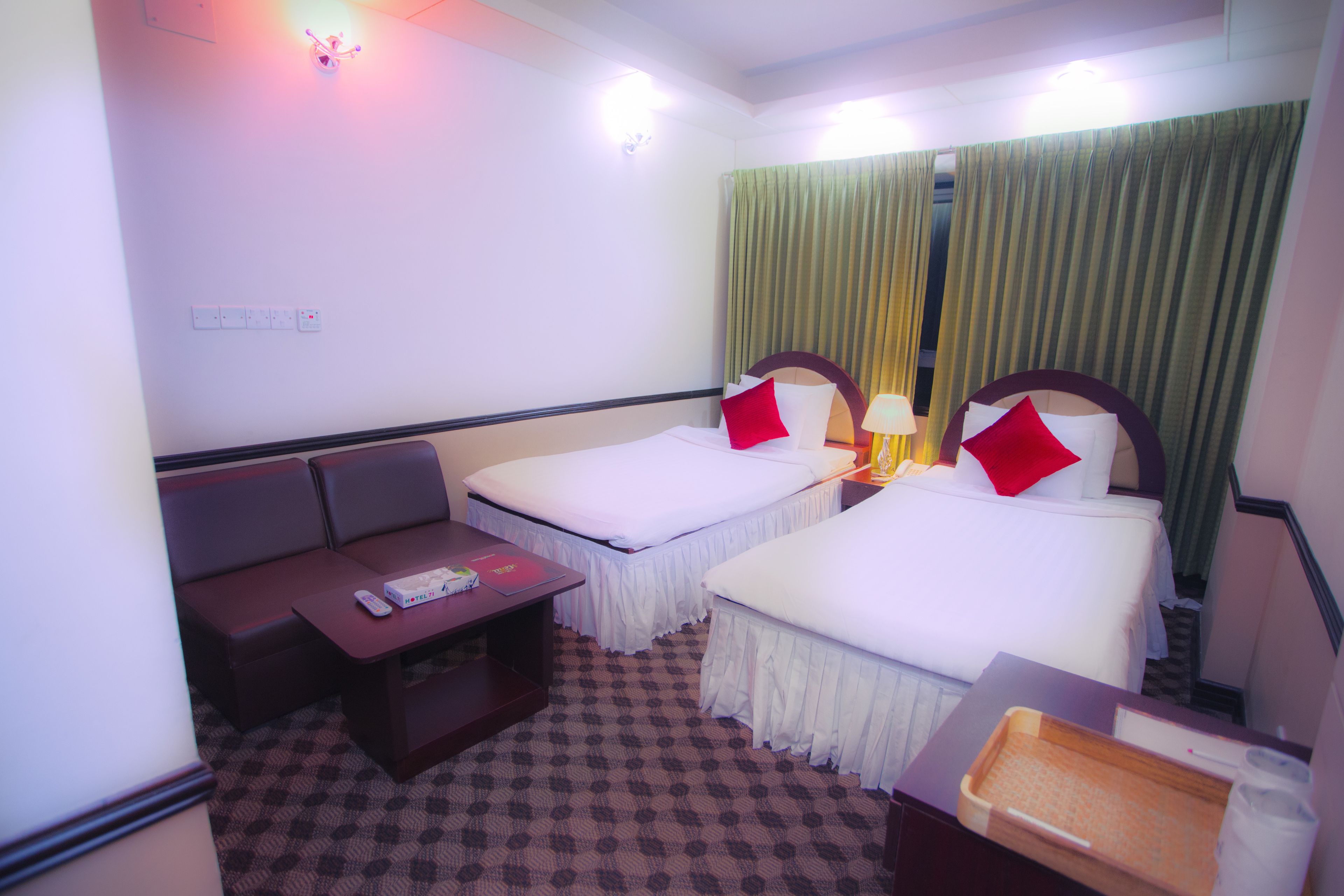 A hotel room with two beds, a sofa, a small table, and a tray table.