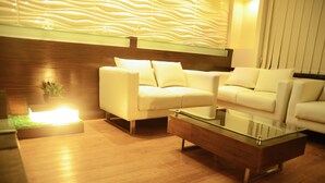 Ein modernes Wohnzimmer mit einem Glastisch, zwei weißen Sofas und einer Wand als Holzakzent.
