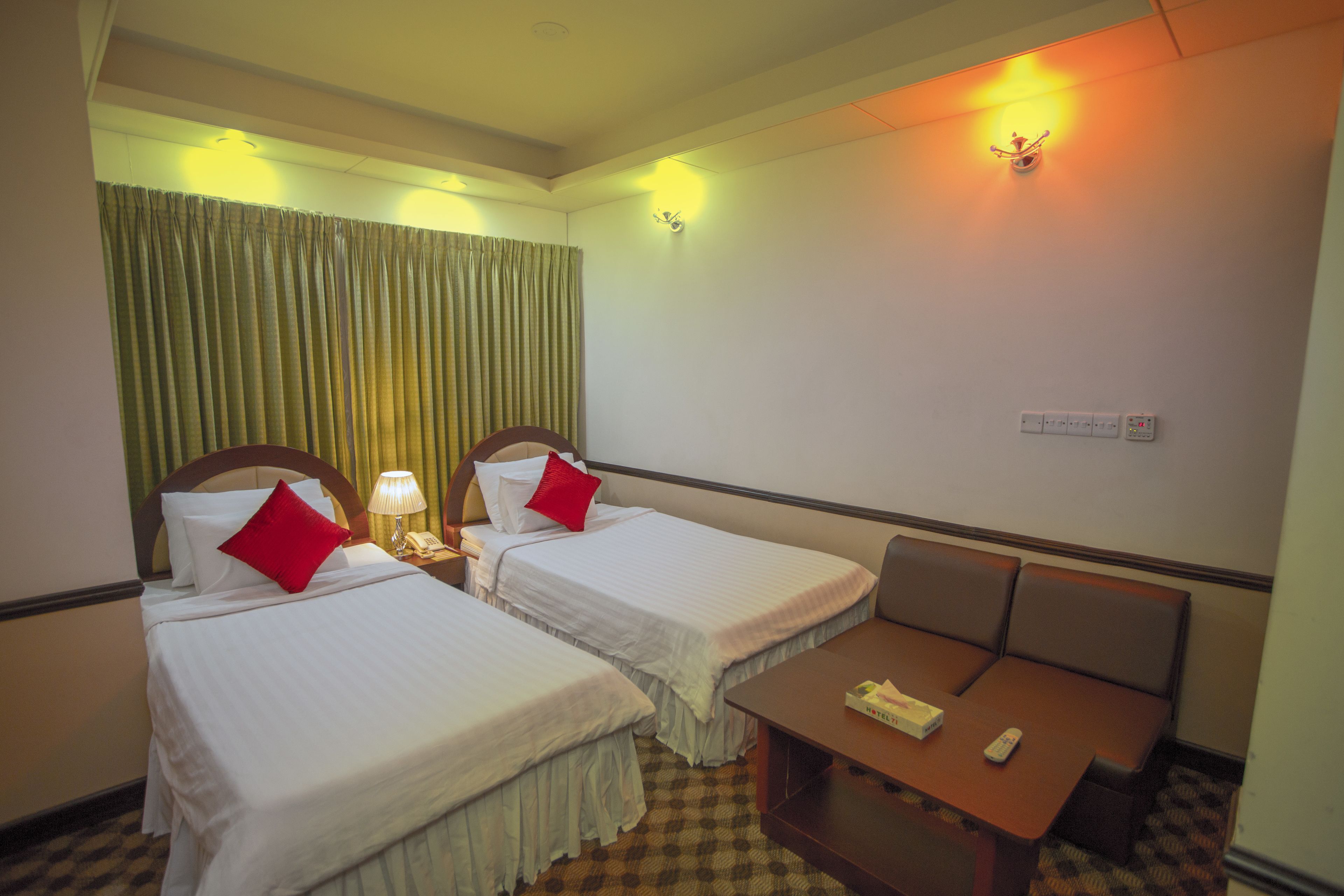 A hotel room with two beds, a small table, and a chair.