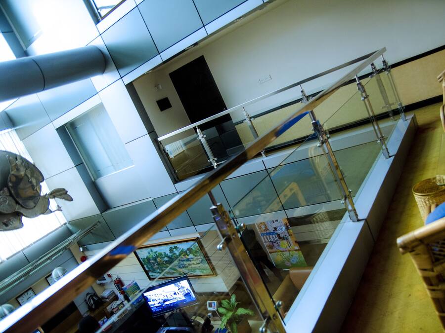 A high-ceilinged lobby with a glass railing, a reception desk, and a blue cushioned chair.
