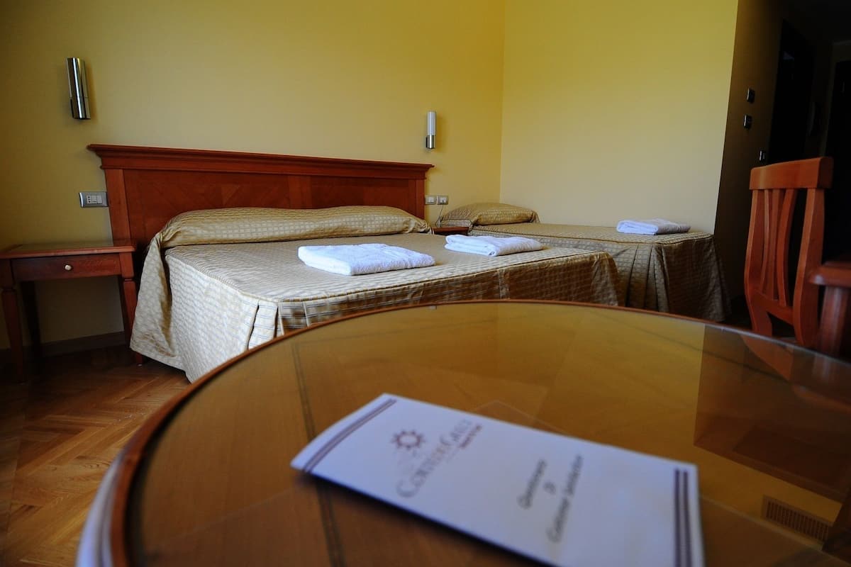 Ein Hotelzimmer mit zwei Betten, einem Holzkopfstück, Nachttischen und einem runden Tisch mit einer Speisekarte.
