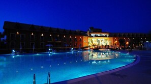 A swimming pool with lounge chairs and umbrellas, surrounded by buildings with a traditional architectural style. - Corte dei Greci Resort & Spa (Cariati)