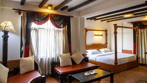 A traditional four-poster bed, a daybed, and a small table with a lamp in a room with exposed wooden beams and a tiled floor. - Hotel Ganesh Himal (Kathmandu)