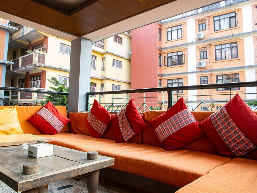 A balcony with a sofa and table, overlooking a multi-story building with balconies and windows.