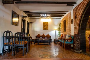 Un interior acogedor con un banco, sillas y un sofá de madera, una pared de ladrillo y un techo de madera.