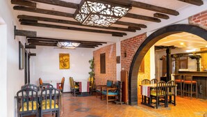 A restaurant with exposed wooden beams, brick walls, and tiled flooring. There are tables and chairs arranged for dining. - Hotel Ganesh Himal (Kathmandu)